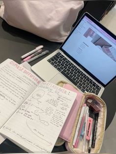 an open laptop computer sitting on top of a desk next to a notebook and pen