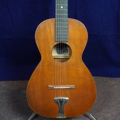 an old guitar sitting on top of a stand in front of a blue background,