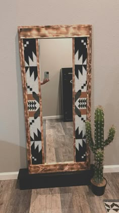 a mirror sitting on top of a wooden floor next to a cactus