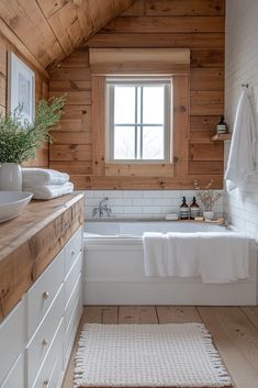 a bathroom with wooden walls and flooring, white bathtub next to the window