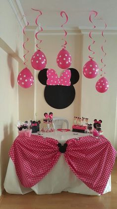 a minnie mouse birthday party with pink and white balloons, polka dot table cloths and decorations