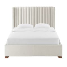 a white bed with an upholstered headboard and two pillows on the side