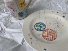 two plates with designs on them next to a coffee cup and saucer decorated with balloons