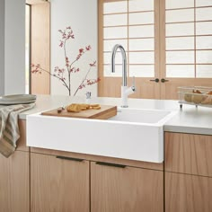 a white kitchen sink sitting under a window next to a counter top with food on it