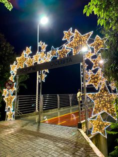 an archway decorated with lights and stars on the side of a road in front of a street sign