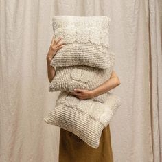 a woman holding three pillows in front of her face