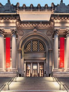 the entrance to an art museum with steps leading up to it and red banners hanging from the ceiling