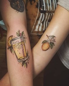 two people with tattoos on their arms holding each other's hands and one has a drink in it