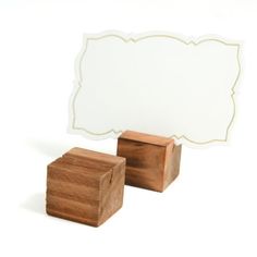 two wooden blocks are next to a white card holder with a blank sign on it