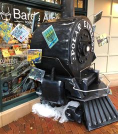 an old fashioned steam engine on display in front of a store window with stickers all over it