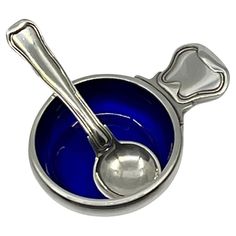 a blue bowl with two spoons in it and a bone on the side,