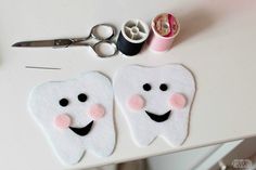 two tooth shaped cookies sitting on top of a white table next to scissors and thread