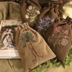 three bags with embroidered designs on them sitting on a bed next to an open book