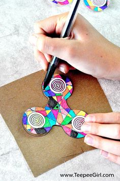 someone is making an art project with colored paper and scissors on top of a piece of cardboard