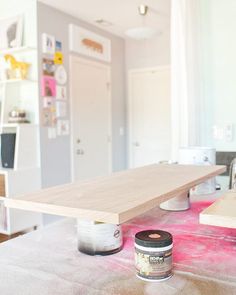 a table with some paint on top of it next to a shelf and cabinets in the background