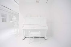 a white piano sitting in the middle of a room with two stools next to it