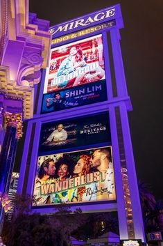 a tall tower with several movie posters lit up on it's sides at night