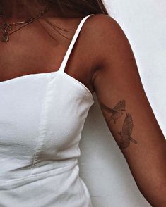 a woman's arm with a bird tattoo on the left side of her arm