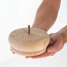 a person holding a wooden object with screws in their hands, on a white background