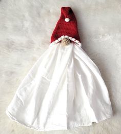 a white dress with a red gnome hat on it's head is laying on a fur surface