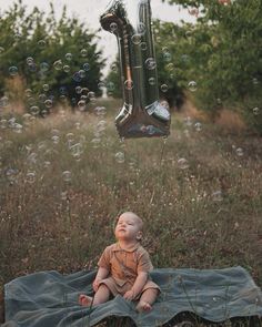 a baby is sitting on a blanket in the grass with bubbles coming out of it