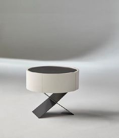 a white table with a black top sitting on a gray floor next to a wall