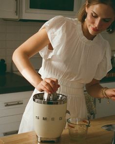 a woman is mixing something in a blender