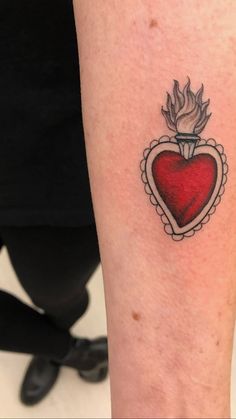 a red heart tattoo on the arm with a small bird in it's center