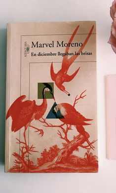 there is a book with birds on it next to a pink flower and a pen