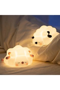 two sheep shaped lights sitting on top of a bed