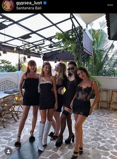 four beautiful young women standing next to each other in front of an outdoor patio area