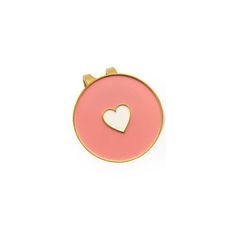 a pink and gold brooch with a white heart on the center, against a white background