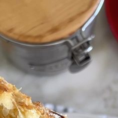 a piece of food sitting on top of a white plate next to a metal pan