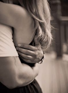 two people hugging each other in black and white photo with wood flooring behind them