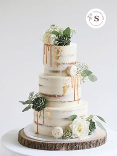 a three tiered cake with white flowers and greenery