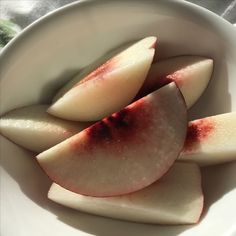 sliced apples sit in a white bowl on a table