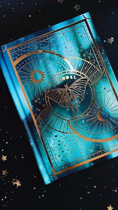 a blue and gold playing card with stars in the sky behind it on a black surface