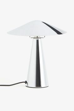 a white table lamp with a black cord on it's end and a silver base