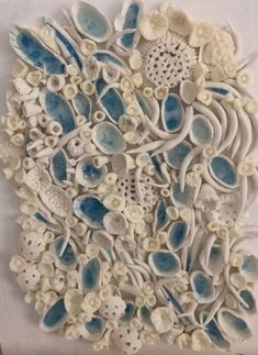 a white and blue wall hanging on the side of a wooden frame with sea shells in it