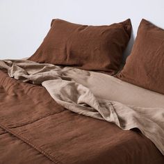 an unmade bed with brown sheets and pillows