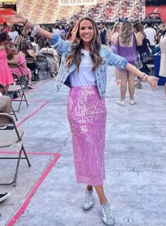 a woman standing in front of a crowd wearing a purple sequin skirt