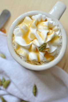 a cup filled with whipped cream and toppings on top of a white napkin next to a spoon