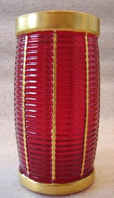 a red and gold vase sitting on top of a table