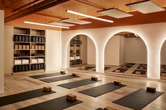 an empty yoga room with rows of mats on the floor and shelves full of bottles