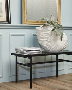 a vase sitting on top of a black table next to a framed painting and books