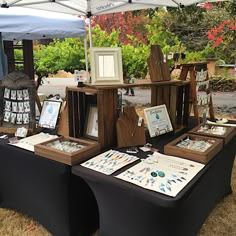 a table with several items on it under a tent at an outdoor art show in the park