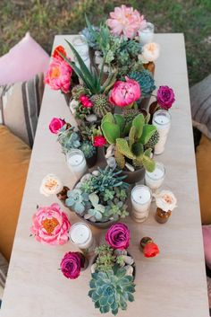 a table topped with succulents and candles on top of a wooden table