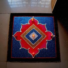 a blue and red area rug on the floor with a candle lit up in it