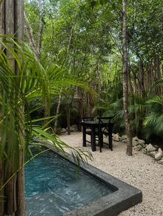 an outdoor hot tub in the middle of a forest with tables and chairs around it