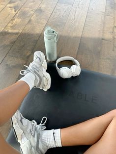 a woman sitting on top of a yoga mat with headphones and a cup of coffee